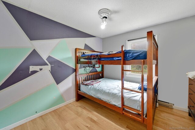 18 Robbie Rd, East Haddam, CT 06469 - bedroom featuring wood finished floors, a baseboard heating unit, baseboards, and a textured ceiling