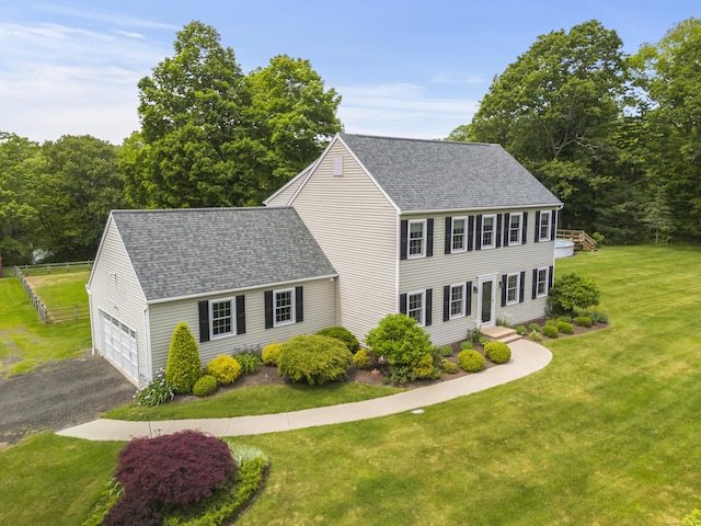 colonial-style house featuring roof with shingles, driveway, and an attached garage