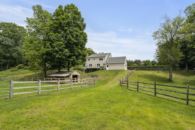 view of green lawn featuring an outbuilding, a rural view, and an exterior structure