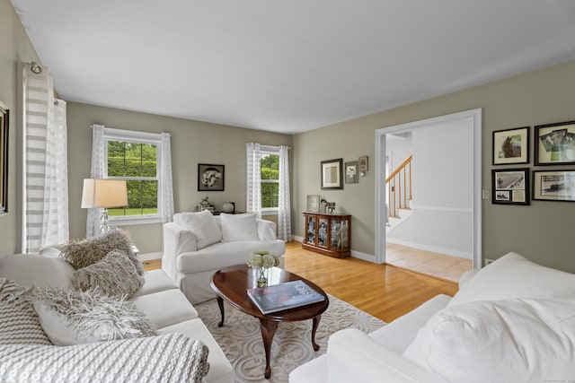 living area featuring plenty of natural light, light wood-style flooring, stairway, and baseboards