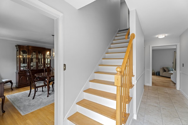 stairway featuring a chandelier, wood finished floors, and baseboards