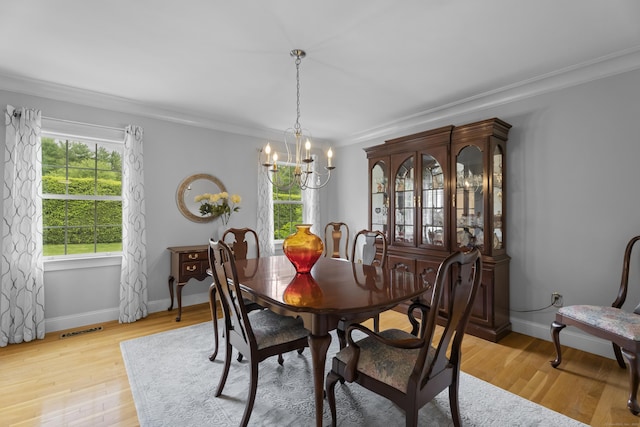 dining space featuring a chandelier, crown molding, light wood-style floors, and baseboards