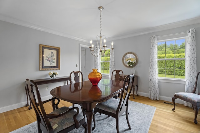 dining area featuring a chandelier, ornamental molding, light wood-style flooring, and baseboards