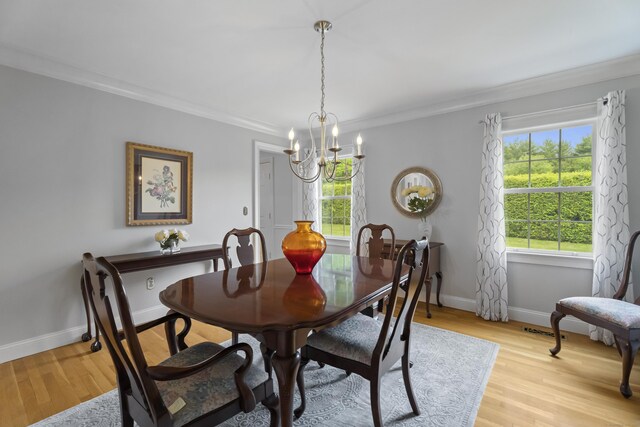 dining area featuring a chandelier, ornamental molding, light wood-style flooring, and baseboards
