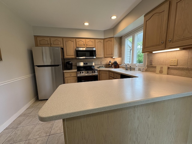 kitchen with stainless steel appliances, light countertops, a sink, decorative backsplash, and light tile patterned floors