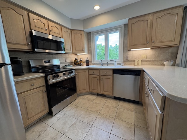 kitchen with appliances with stainless steel finishes, a sink, decorative backsplash, light countertops, and recessed lighting