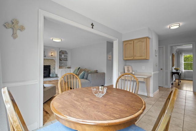 dining room with built in shelves, light tile patterned floors, and baseboards