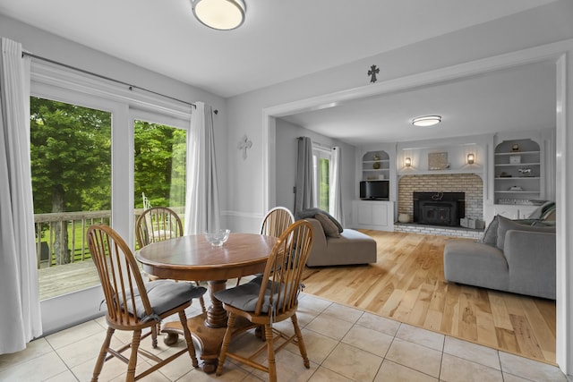 dining space with light tile patterned floors, healthy amount of natural light, a brick fireplace, and built in features