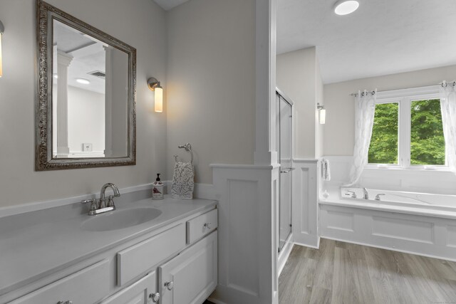 full bathroom featuring a shower stall, wood finished floors, a garden tub, and vanity