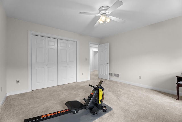 exercise area featuring ceiling fan, light carpet, and baseboards