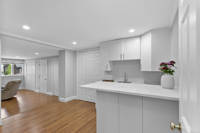 42 Woodledge Rd, Stamford, CT 06907 - kitchen with white cabinetry, light wood-style flooring, recessed lighting, light stone counters, and a peninsula