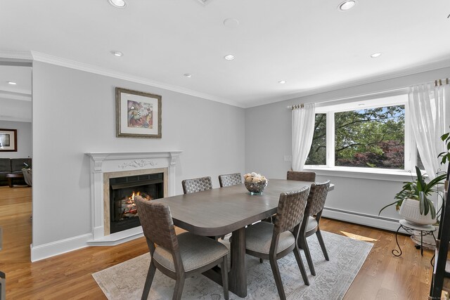 42 Woodledge Rd, Stamford, CT 06907 - dining area featuring a lit fireplace, ornamental molding, recessed lighting, light wood-type flooring, and a baseboard radiator