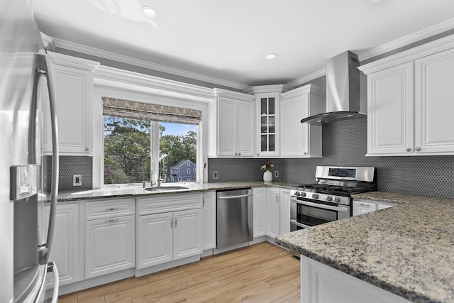 42 Woodledge Rd, Stamford, CT 06907 - kitchen featuring stainless steel appliances, wall chimney exhaust hood, white cabinetry, light stone counters, and crown molding