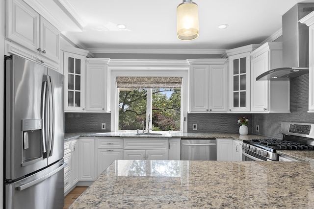 42 Woodledge Rd, Stamford, CT 06907 - kitchen with stainless steel appliances, wall chimney range hood, white cabinetry, ornamental molding, and glass insert cabinets