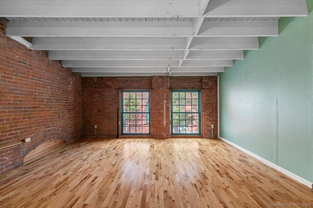 1 Front St Unit 204, New Haven, CT 06513 - unfurnished living room with beam ceiling, wood finished floors, brick wall, and baseboards