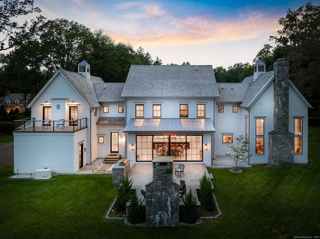 300 Hollow Tree Ridge Rd, Darien, CT 06820 - back of property at dusk featuring a standing seam roof, a chimney, a yard, metal roof, and roof with shingles