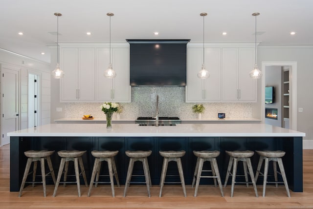 300 Hollow Tree Ridge Rd, Darien, CT 06820 - kitchen with backsplash, a spacious island, light countertops, hanging light fixtures, and light wood-type flooring