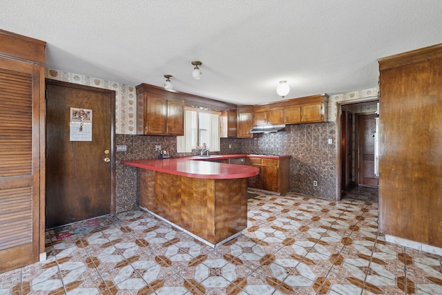 24 Goff St, Waterbury, CT 06704 - kitchen with a sink, a peninsula, brown cabinets, a textured ceiling, and under cabinet range hood
