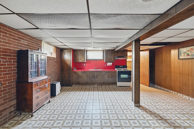 24 Goff St, Waterbury, CT 06704 - kitchen featuring white range oven, a drop ceiling, brick wall, wooden walls, and light flooring