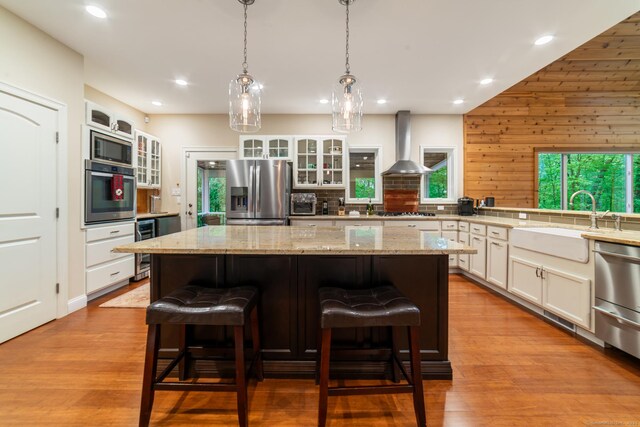 732 Hulls Hill Rd, Southbury, CT 06488 - kitchen featuring stainless steel appliances, wall chimney exhaust hood, a sink, a kitchen bar, and recessed lighting