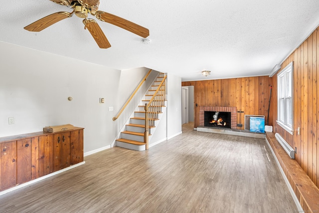 33 Deer Park Rd, Simsbury, CT 06089 - unfurnished living room featuring a textured ceiling, wood finished floors, wood walls, a fireplace, and baseboards