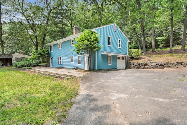 33 Deer Park Rd, Simsbury, CT 06089 - view of front of house with asphalt driveway, a chimney, a garage, and view of scattered trees
