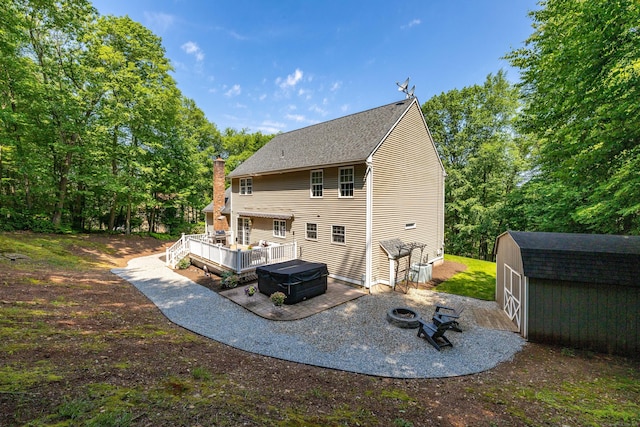 1382 Cedar Swamp Rd, Coventry, CT 06238 - rear view of property with a deck, a fire pit, a patio area, a chimney, and a shingled roof