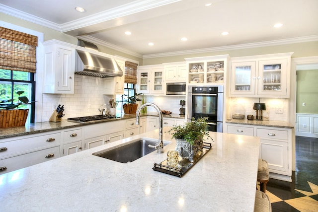 2683 Bronson Rd, Fairfield, CT 06824 - kitchen featuring wall chimney exhaust hood, appliances with stainless steel finishes, white cabinetry, glass insert cabinets, and ornamental molding
