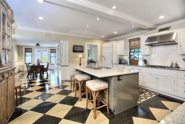 2683 Bronson Rd, Fairfield, CT 06824 - kitchen featuring wall chimney exhaust hood, recessed lighting, a kitchen breakfast bar, white cabinetry, and stainless steel gas stovetop
