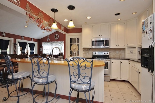 2 Tamshell Dr, Kent, CT 06757 - kitchen featuring appliances with stainless steel finishes, light tile patterned floors, backsplash, a kitchen breakfast bar, and vaulted ceiling