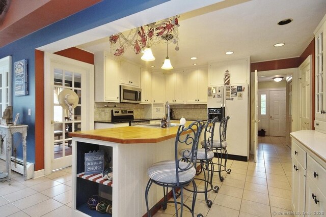 2 Tamshell Dr, Kent, CT 06757 - kitchen featuring appliances with stainless steel finishes, butcher block countertops, light tile patterned flooring, backsplash, and a sink