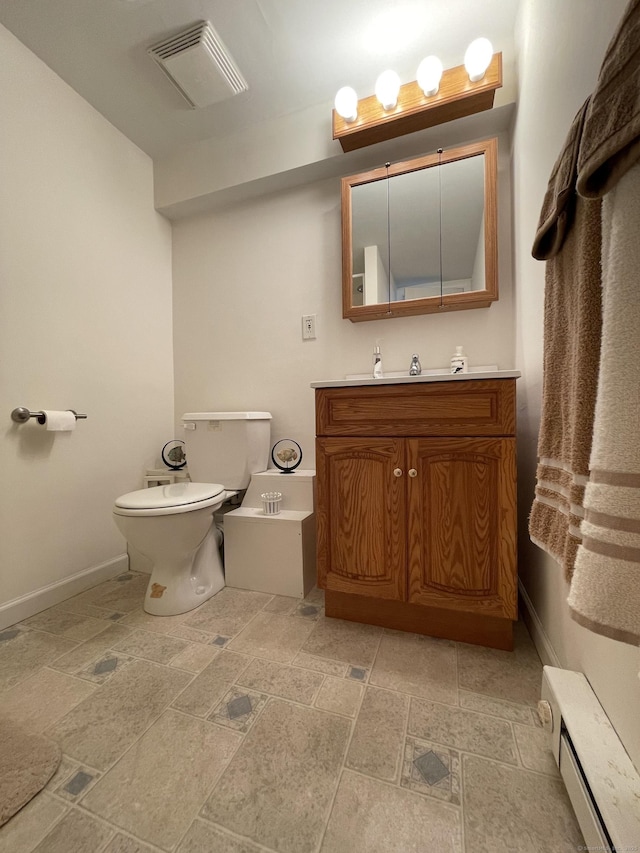 268 Hartford Tpke Apt A2, Tolland, CT 06084 - bathroom featuring baseboard heating, vanity, toilet, stone tile floors, and baseboards