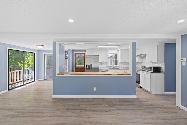 157 Mile Creek Rd, Old Lyme, CT 06371 - kitchen with stainless steel appliances, wood counters, crown molding, under cabinet range hood, and white cabinetry