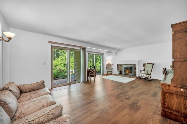 living area with an AC wall unit, dark wood-type flooring, and a brick fireplace