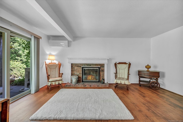 sitting room with a wall mounted air conditioner, wood finished floors, and a fireplace