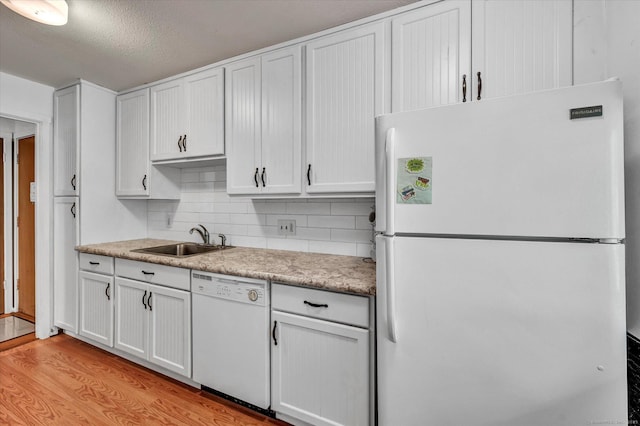 kitchen with white appliances, a sink, light wood-style floors, white cabinets, and a textured ceiling