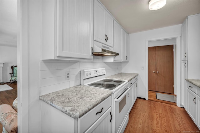 kitchen featuring electric stove, under cabinet range hood, light wood finished floors, and white cabinetry