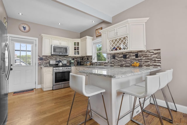 100 Boston Ter, Bridgeport, CT 06610 - kitchen featuring appliances with stainless steel finishes, a peninsula, a breakfast bar, light wood finished floors, and decorative backsplash