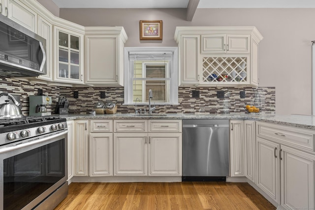 100 Boston Ter, Bridgeport, CT 06610 - kitchen with appliances with stainless steel finishes, a sink, light wood finished floors, tasteful backsplash, and light stone countertops