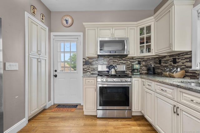 100 Boston Ter, Bridgeport, CT 06610 - kitchen with stainless steel appliances, a sink, tasteful backsplash, light wood finished floors, and glass insert cabinets