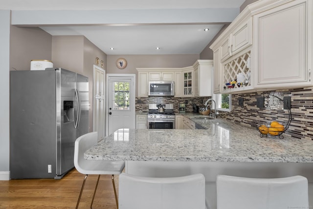 100 Boston Ter, Bridgeport, CT 06610 - kitchen featuring appliances with stainless steel finishes, a peninsula, decorative backsplash, light wood finished floors, and a sink