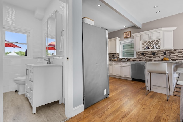 100 Boston Ter, Bridgeport, CT 06610 - kitchen with appliances with stainless steel finishes, white cabinetry, light wood-style flooring, a sink, and beam ceiling