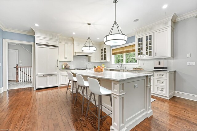 6 Coachlamp Ln, Greenwich, CT 06830 - kitchen with an island with sink, dark wood finished floors, decorative backsplash, baseboards, and glass insert cabinets