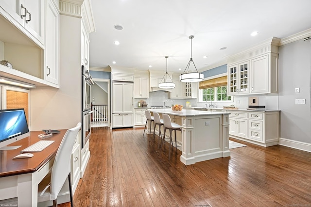 6 Coachlamp Ln, Greenwich, CT 06830 - kitchen featuring glass insert cabinets, a kitchen island with sink, a breakfast bar, dark wood-type flooring, and light countertops