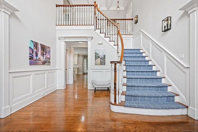 6 Coachlamp Ln, Greenwich, CT 06830 - staircase featuring a decorative wall, wood finished floors, decorative columns, a wainscoted wall, and crown molding