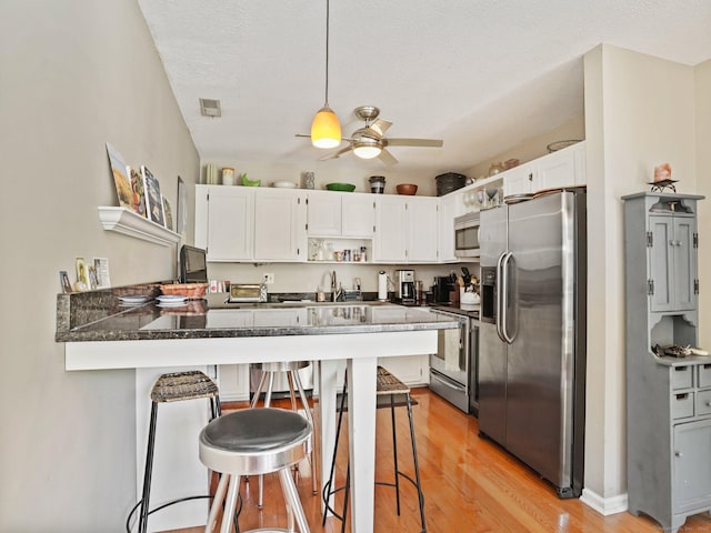 100 Wolfpit Ave Apt 19, Norwalk, CT 06851 - kitchen featuring stainless steel appliances, a peninsula, dark countertops, light wood finished floors, and white cabinets