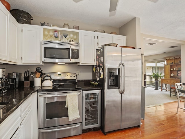 100 Wolfpit Ave Apt 19, Norwalk, CT 06851 - kitchen with stainless steel appliances, wine cooler, white cabinetry, light wood-style floors, and a textured ceiling