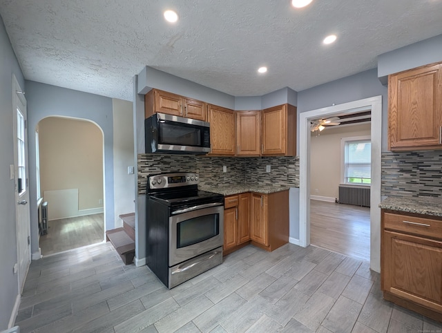 26 Westfield St, Manchester, CT 06042 - kitchen featuring appliances with stainless steel finishes, radiator, arched walkways, light wood-style flooring, and a textured ceiling