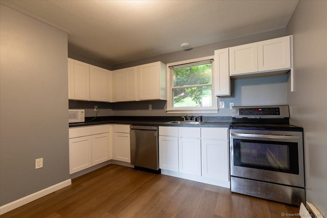270 S Windham Rd Apt 61, Windham, CT 06226 - kitchen with appliances with stainless steel finishes, a sink, dark wood-style floors, dark countertops, and a textured ceiling