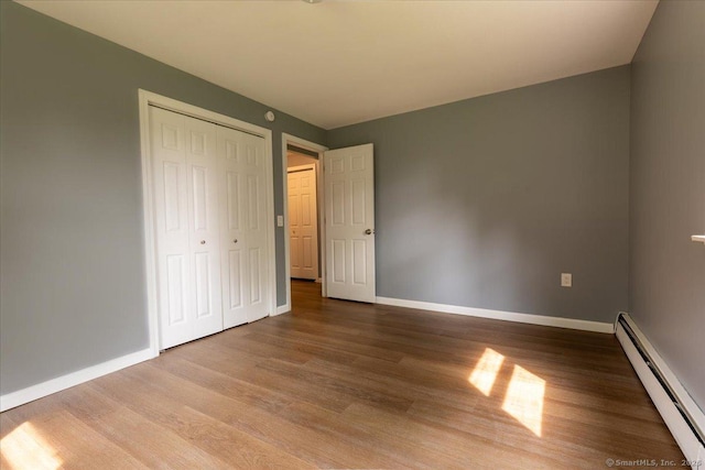 270 S Windham Rd Apt 61, Windham, CT 06226 - unfurnished bedroom with baseboard heating, wood finished floors, baseboards, and a closet